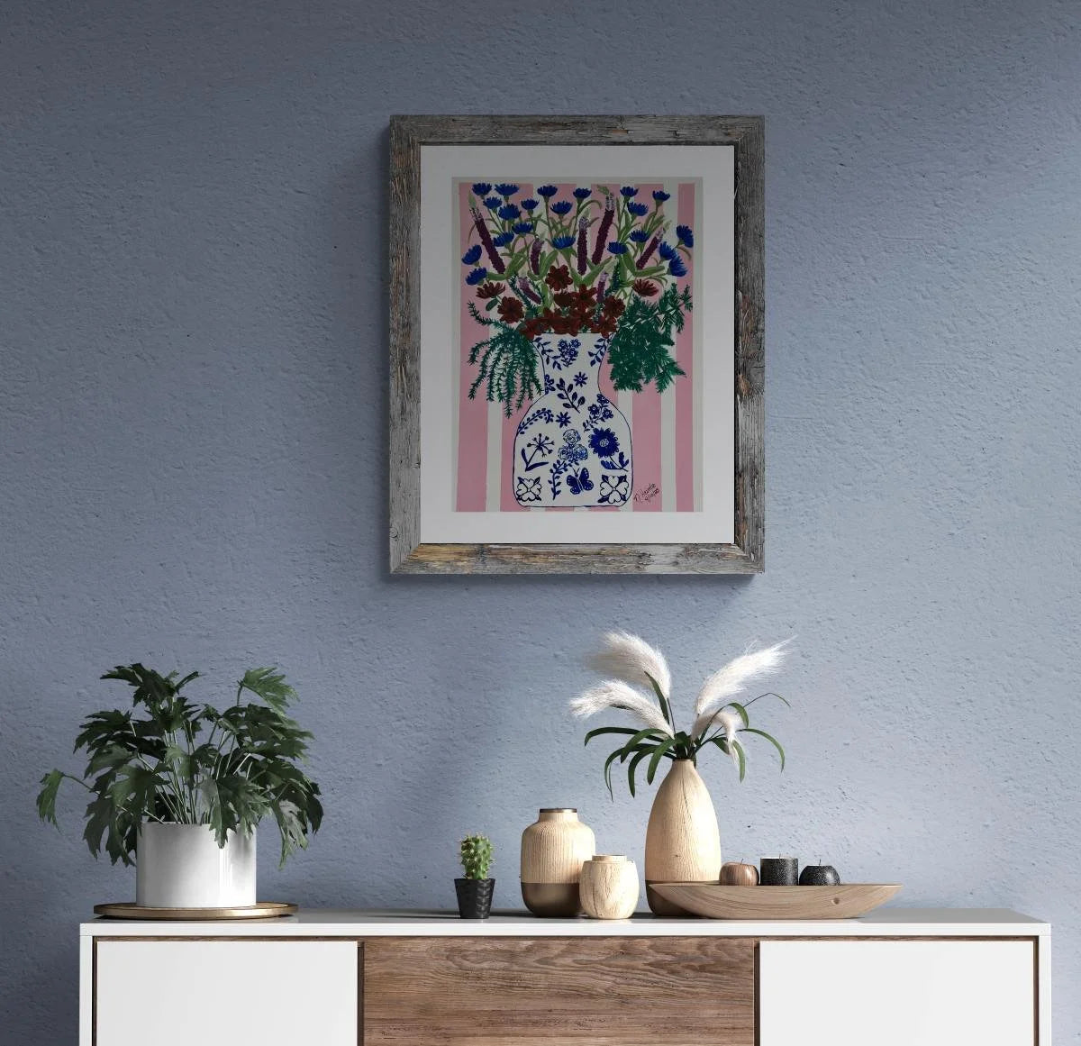 Framed artwork of a floral arrangement on a blue wall above a console table with decorative items.