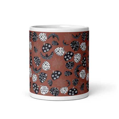 Burnt orange coffee mug with pattern of black and white chinoiserie-style pumpkins, spiders, webs, and bats by Pink Sapphire Designs.